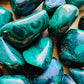 Overhead angle of Grade AA Malachite tumbled stone, for Emotional Healing, showing color depth.