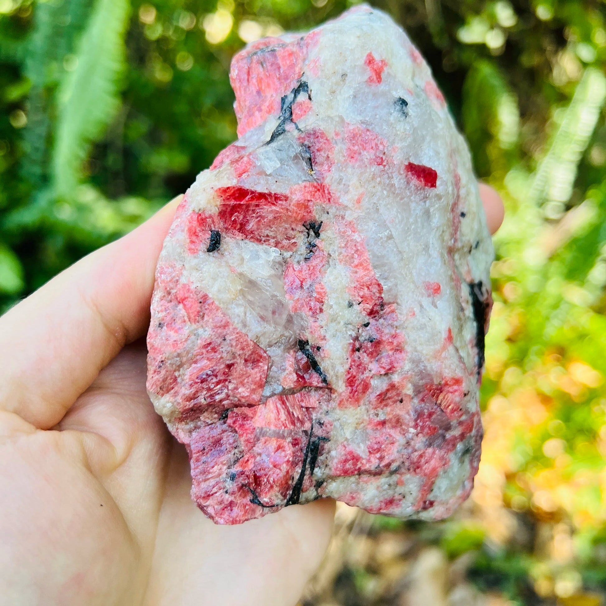 Side-on view of pink Rhodonite specimen, showing natural sheen, to support Emotional Healing.