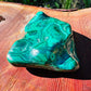 Holding a Malachite specimen, associated with Emotional Healing, with depth visible across the surface.