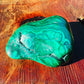 On a soft surface rests a Malachite specimen, from Haut-Katanga, Democratic Republic of the Congo, traditionally used for Manifestation, showing the wear and finish.