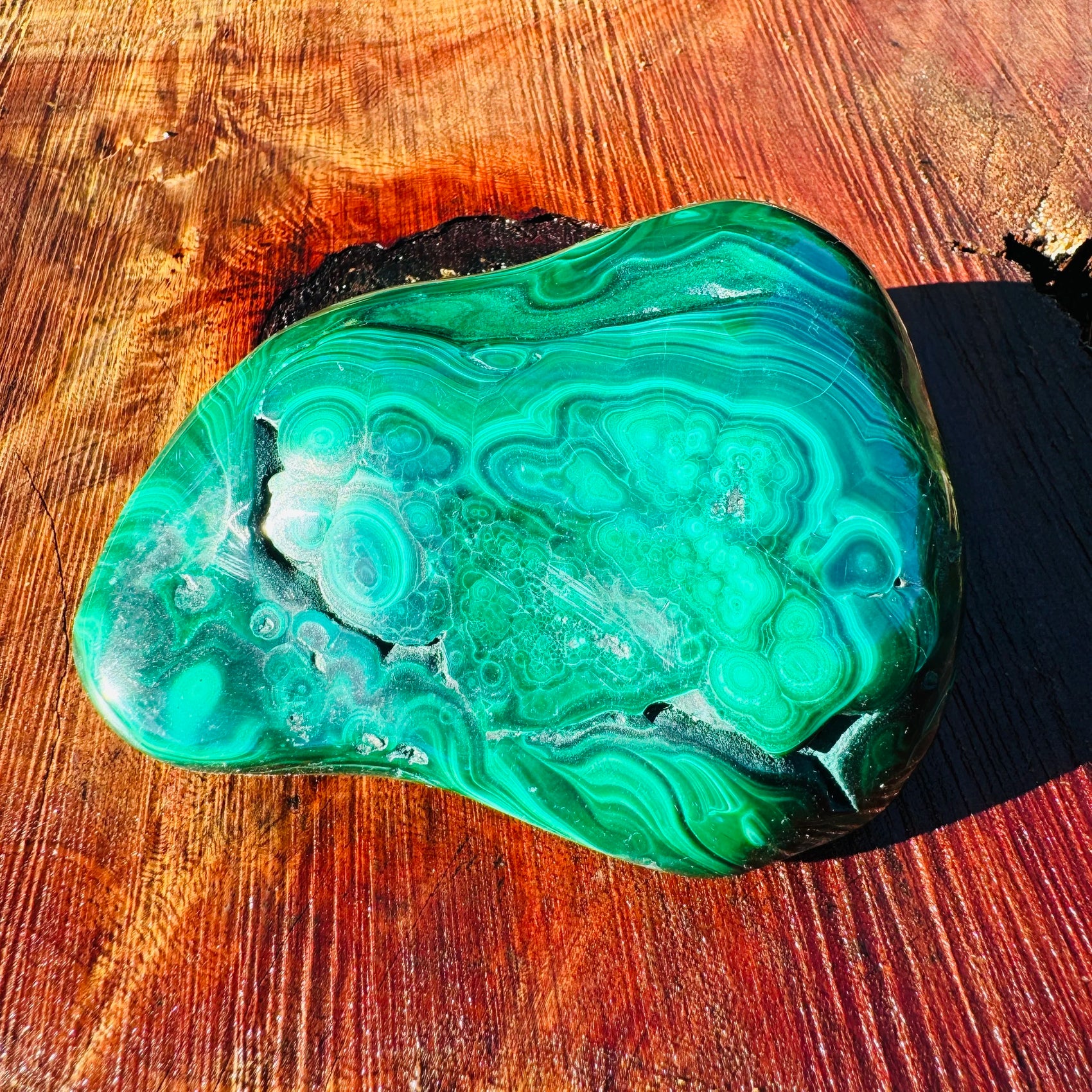 On a soft surface rests a Malachite specimen, from Haut-Katanga, Democratic Republic of the Congo, traditionally used for Manifestation, showing the wear and finish.