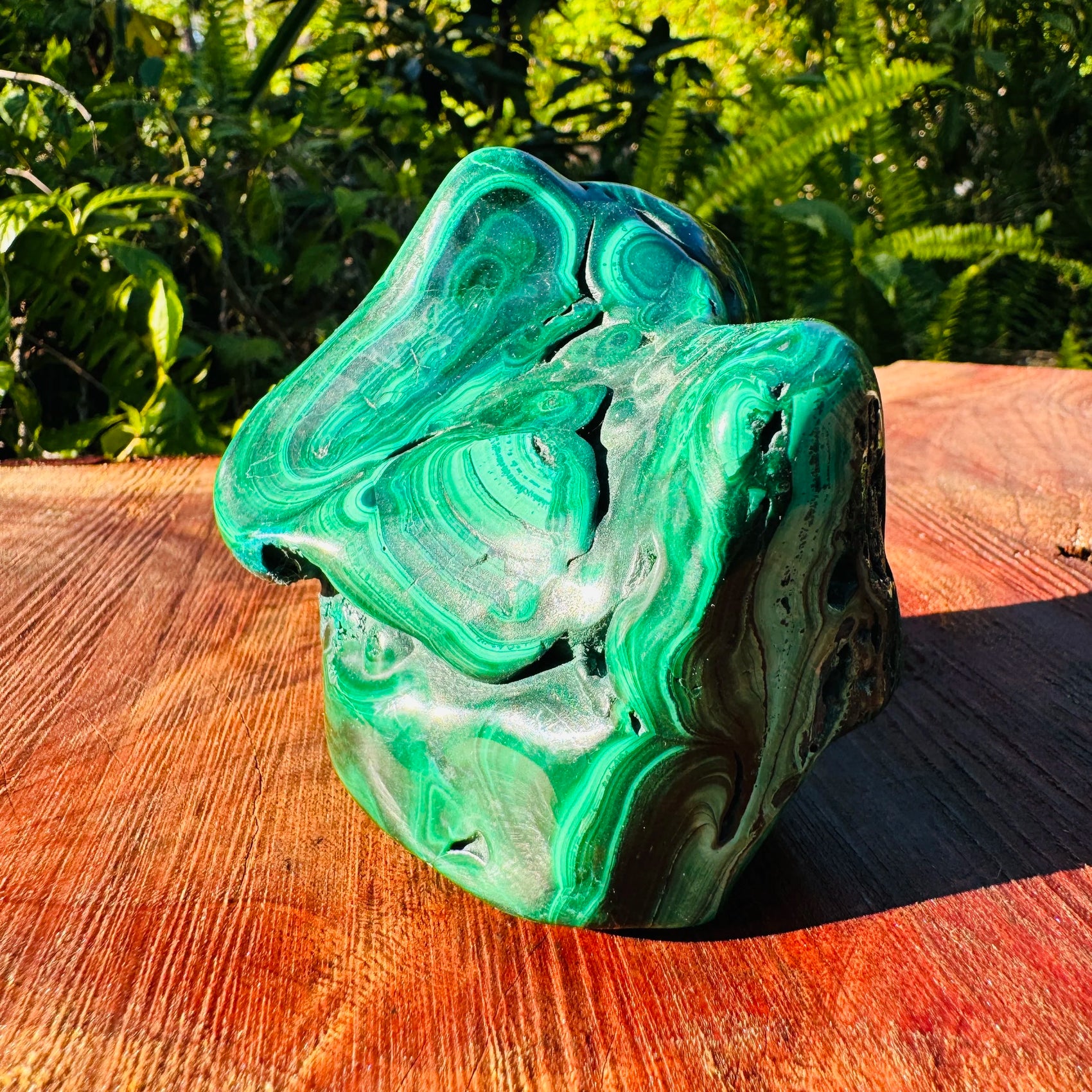 Held in hand is a Malachite specimen, shown for shape and scale.