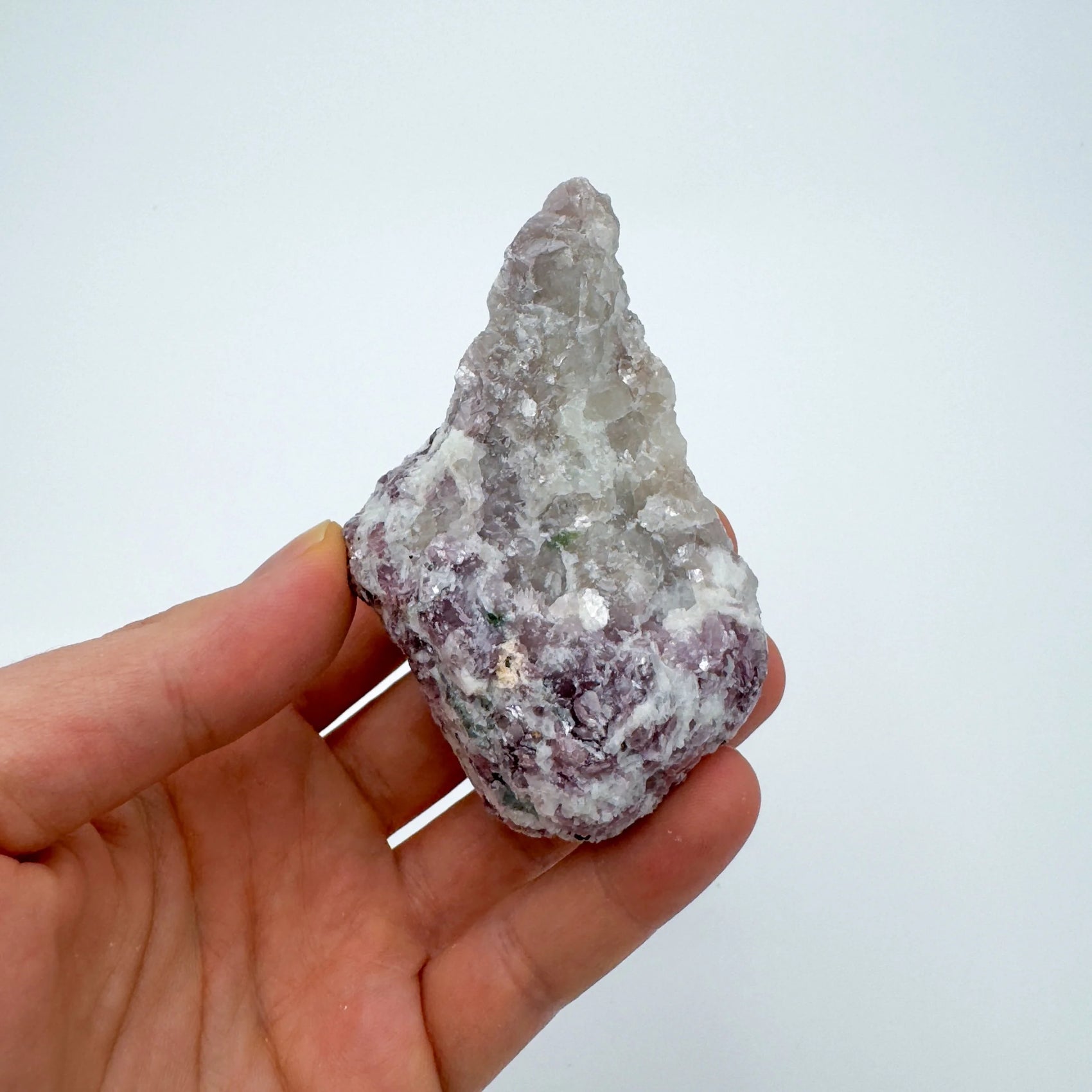 On a soft surface rests a Lepidolite specimen, with surface texture in view.