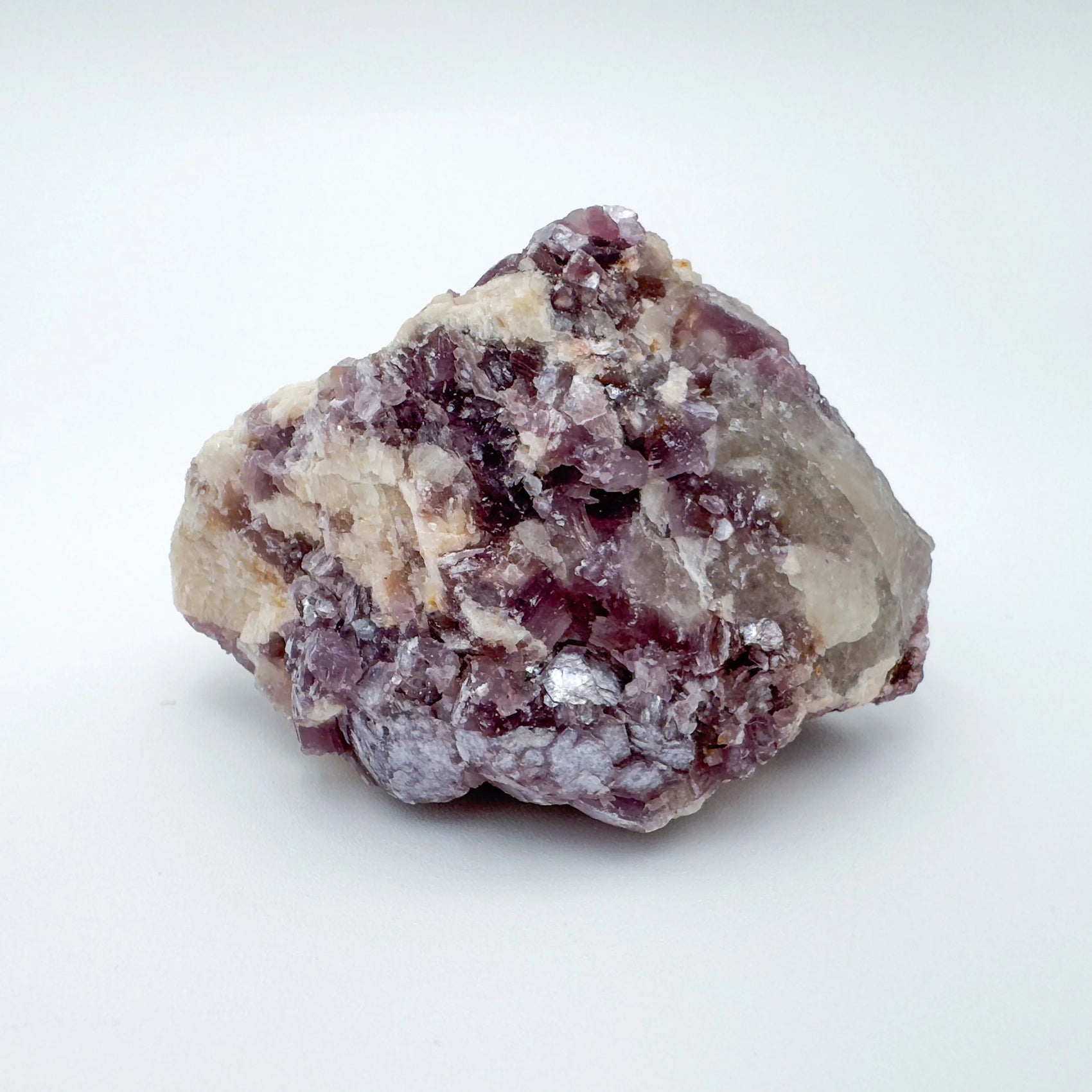 In-hand view of a Lepidolite specimen held against natural backdrop.