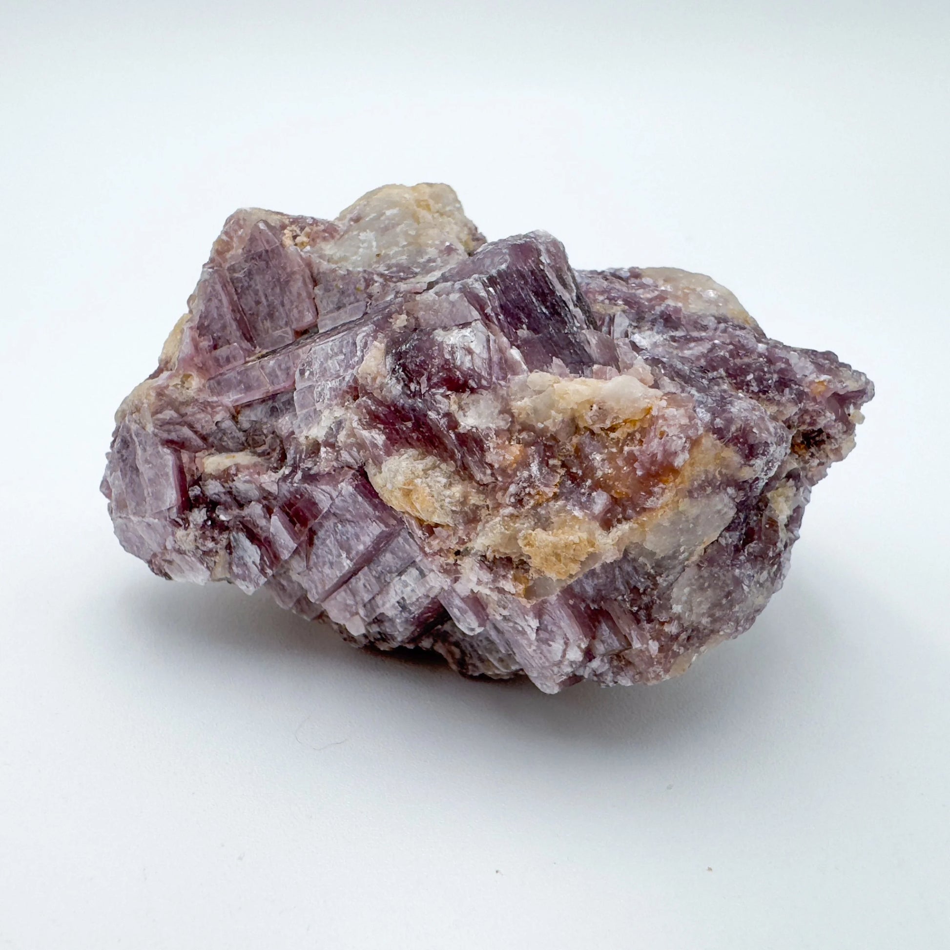 Daylight view of a Lepidolite specimen held against natural backdrop, Brazil-sourced.