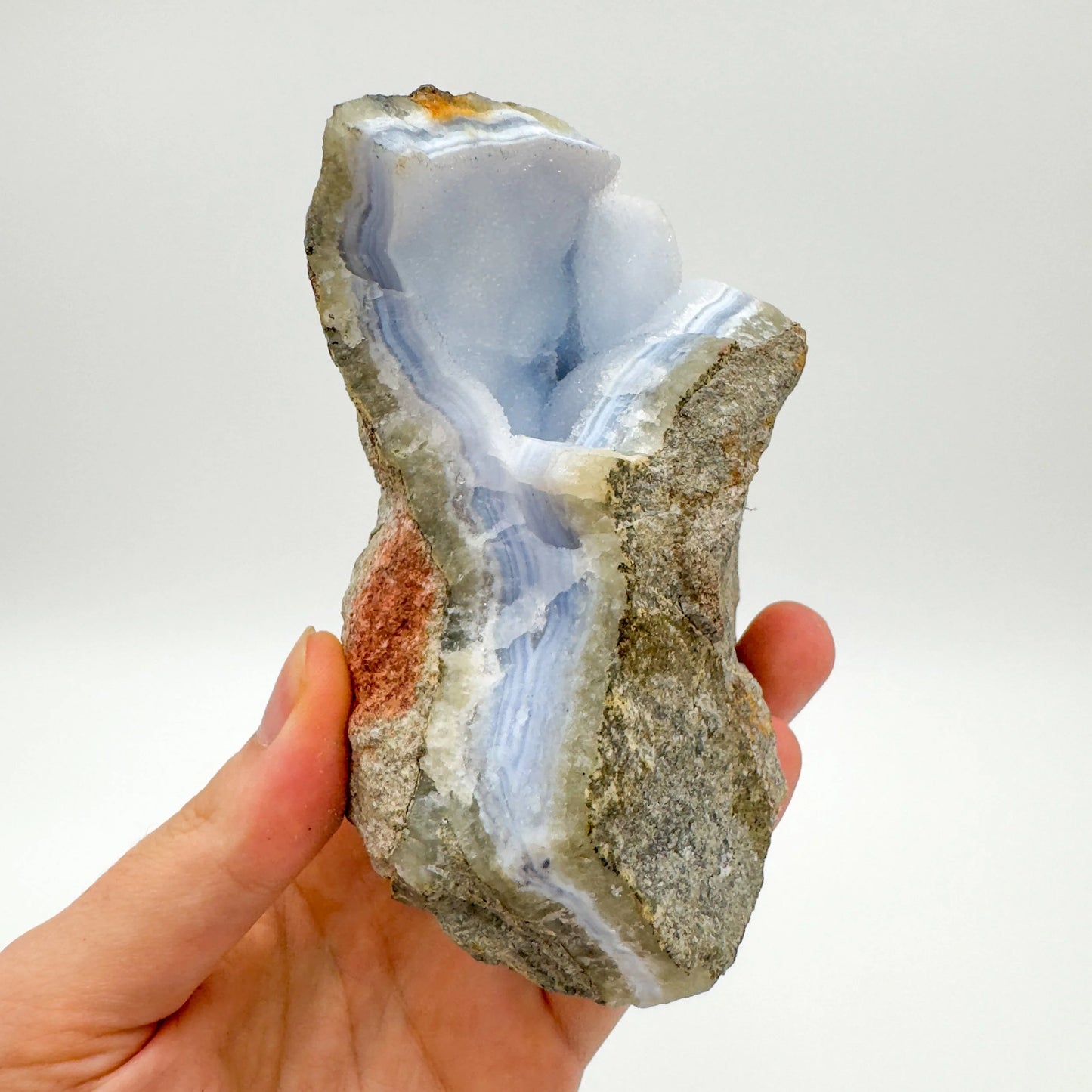 Grade aa blue lace agate geode held in hand for size reference
