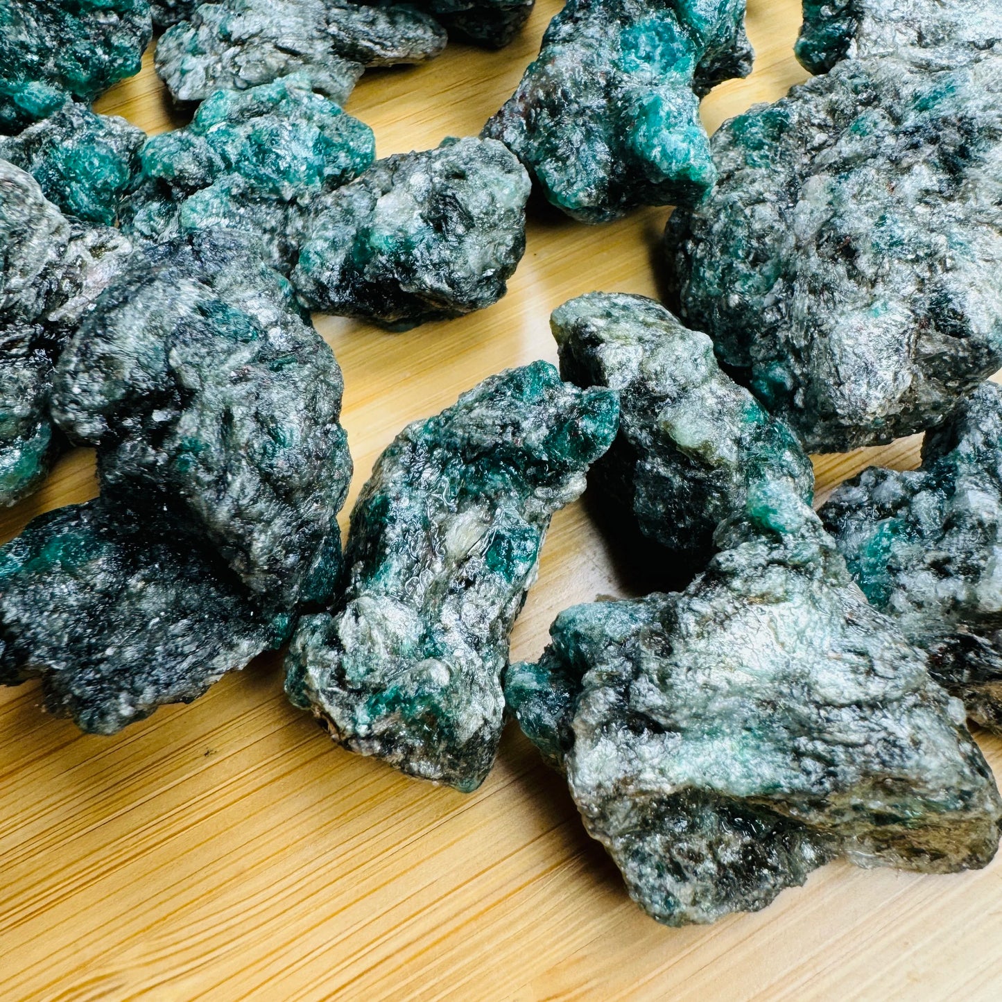 Daylight view of a Emerald raw stone held against natural backdrop.