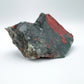 On a soft surface rests a Bloodstone specimen, associated with Grounding, showing natural surface character.