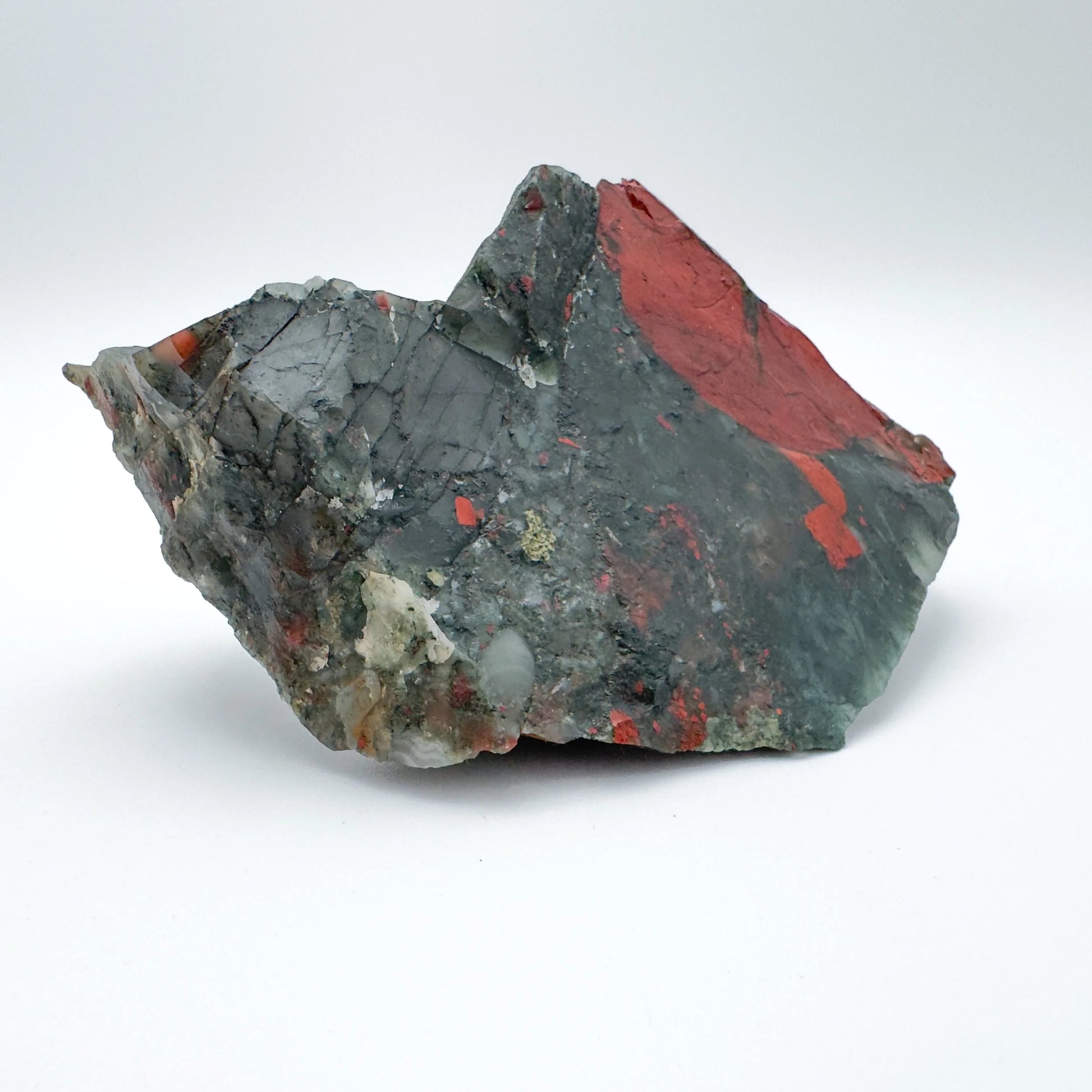 On a soft surface rests a Bloodstone specimen, associated with Grounding, showing natural surface character.