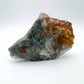Daylight view of a Bloodstone specimen held against natural backdrop, from Hhohho, Eswatini.