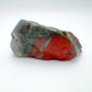 Palm-scale view of a Bloodstone specimen held against natural backdrop.