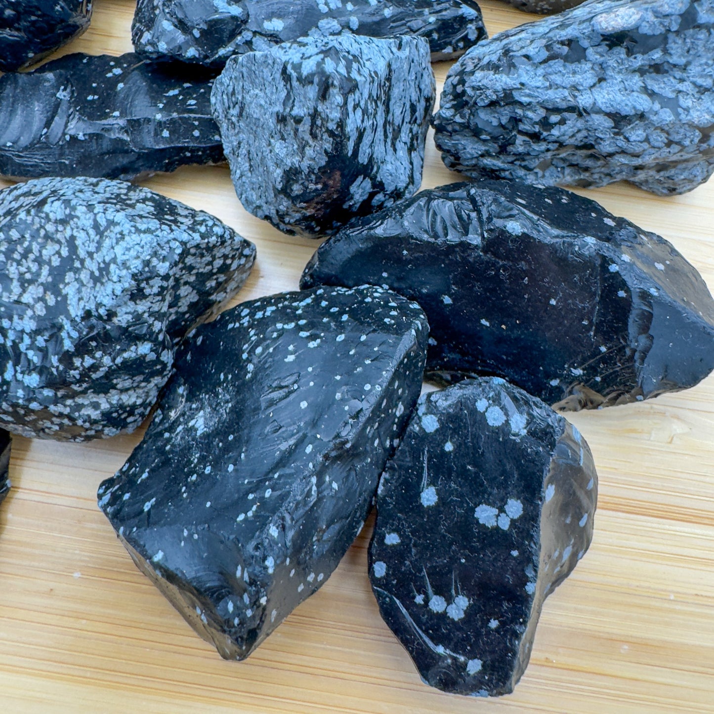 Side-on view of Snowflake Obsidian raw stone, showing natural sheen, traditionally used for Grounding and Emotional Healing.