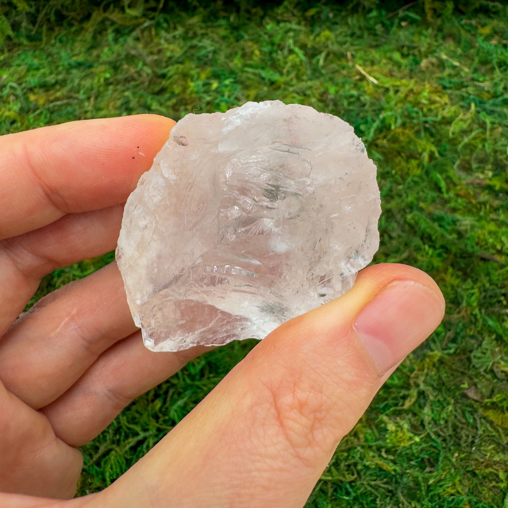 Held in hand is a Clear Quartz raw crystal, from Minas Gerais, Brazil, traditionally used for Manifestation, shown for proportion against the hand.
