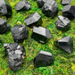 Hand-scale shot of a Black Tourmaline raw stone held against natural backdrop.