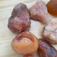 Palm-scale view of a Carnelian raw stone held against natural backdrop, from Malawi.