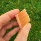 Composed shot of Orange Calcite raw crystal, traditionally used for Energy, set against a soft neutral surface.