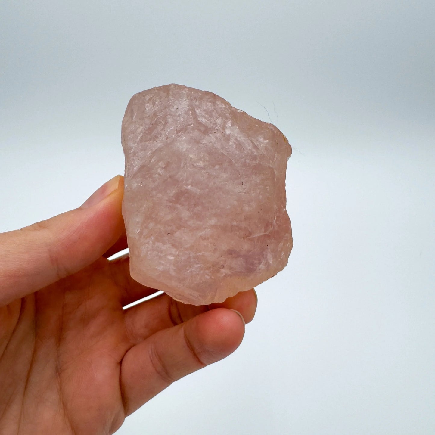 Held in hand is a Rose Quartz specimen, from Alaotra-Mangoro, Madagascar, captured in soft, even lighting.