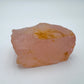 Hand-held view of a Rose Quartz specimen held against natural backdrop.