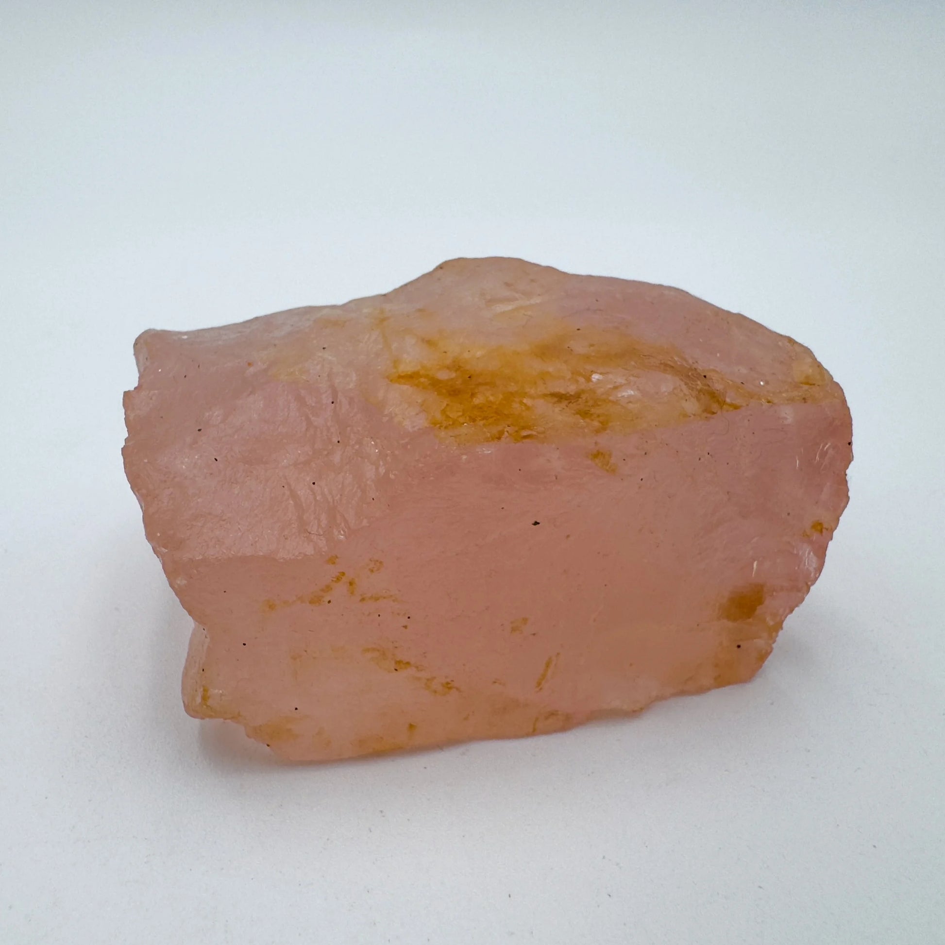 Hand-held view of a Rose Quartz specimen held against natural backdrop.
