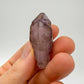 Considered view of Smoky Amethyst raw crystal, from Masvingo, Zimbabwe, shown alongside the hand for scale.