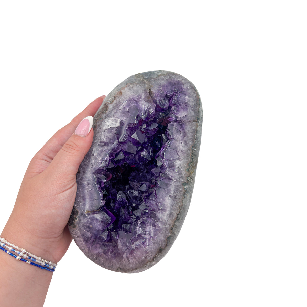 Amethyst polished geode from Uruguay held in an open hand, showing true scale, 5.39 pound closed almond-shaped nodule, specimen 11.