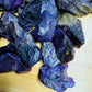 Daylight view of a Stichtite raw stone held against natural backdrop, from Mpumalanga, South Africa.