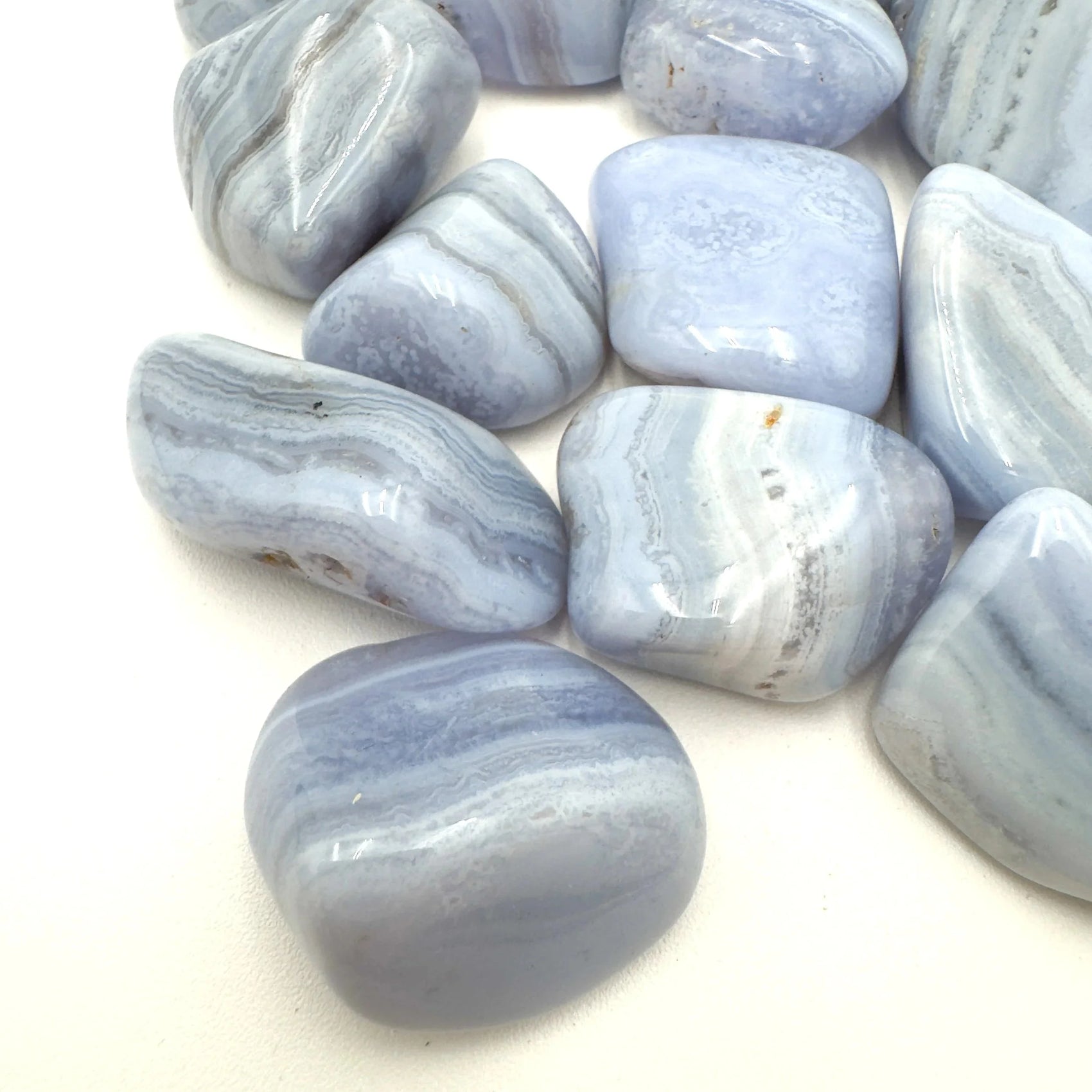 Hand-held view of a Blue Lace Agate tumbled stone, sourced from ǁKaras Region, Namibia.