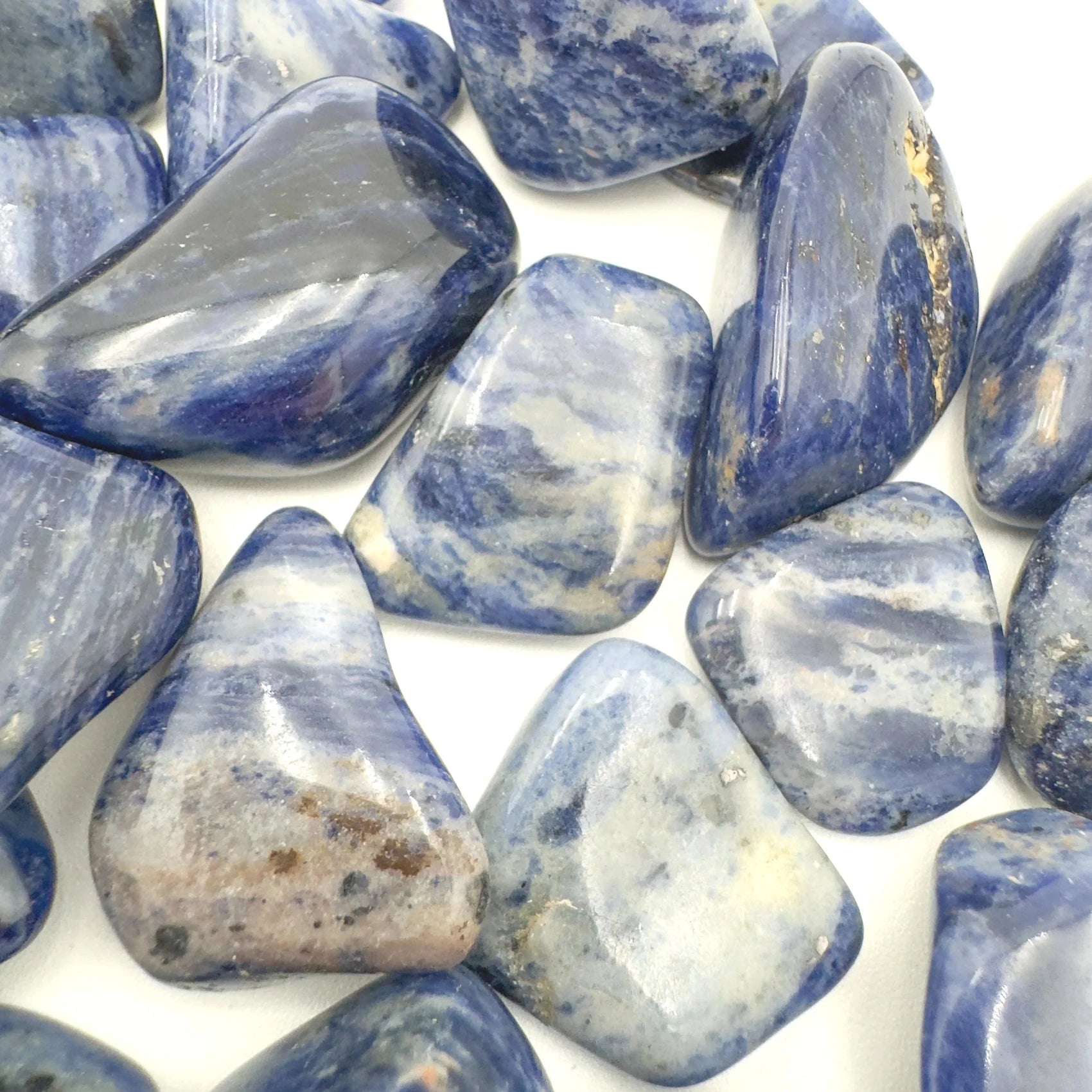Hand-held view of a Sodalite tumbled stone held against natural backdrop.