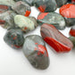 Edge-on view of Bloodstone tumbled stone, linked to Energy and Protection, showing characteristic finish.