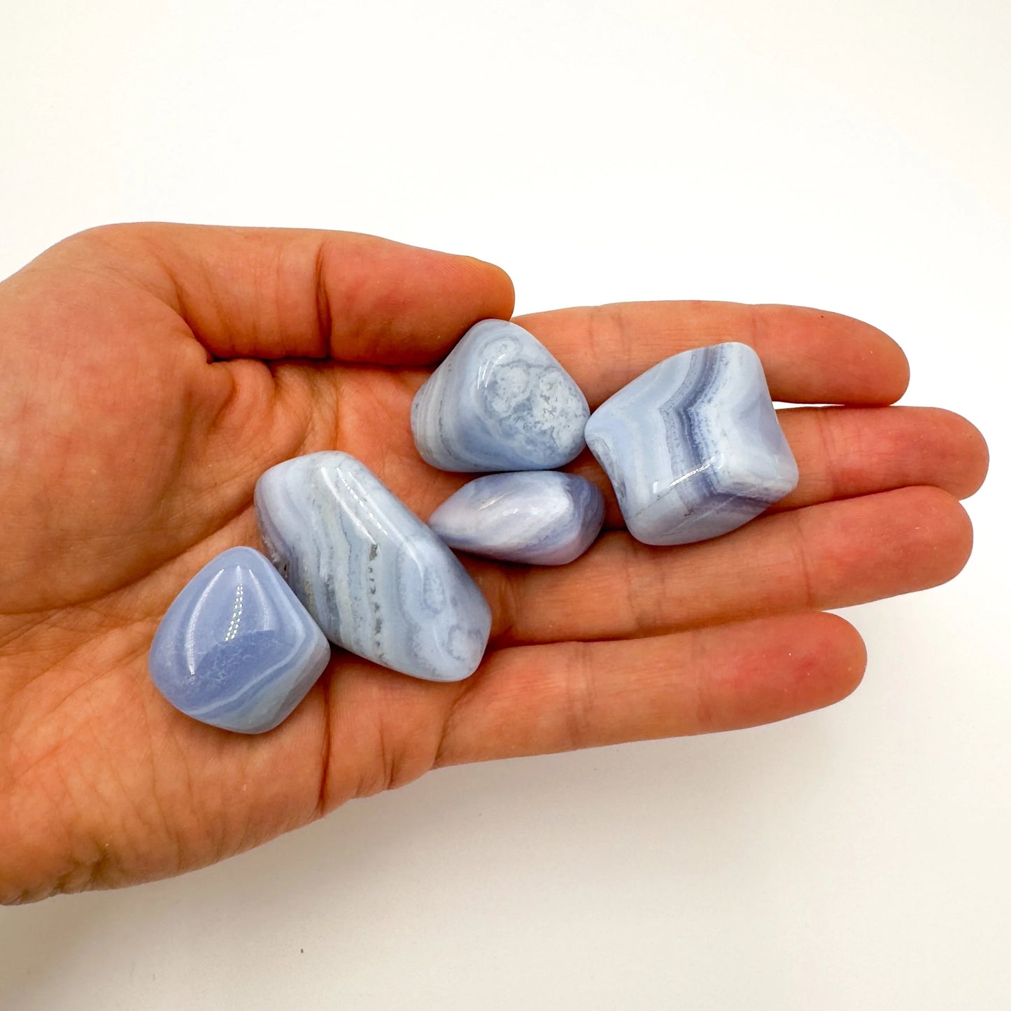 Tabletop view of Blue Lace Agate tumbled stone, from ǁkaras Region, Namibia, in the warmth of daylight.