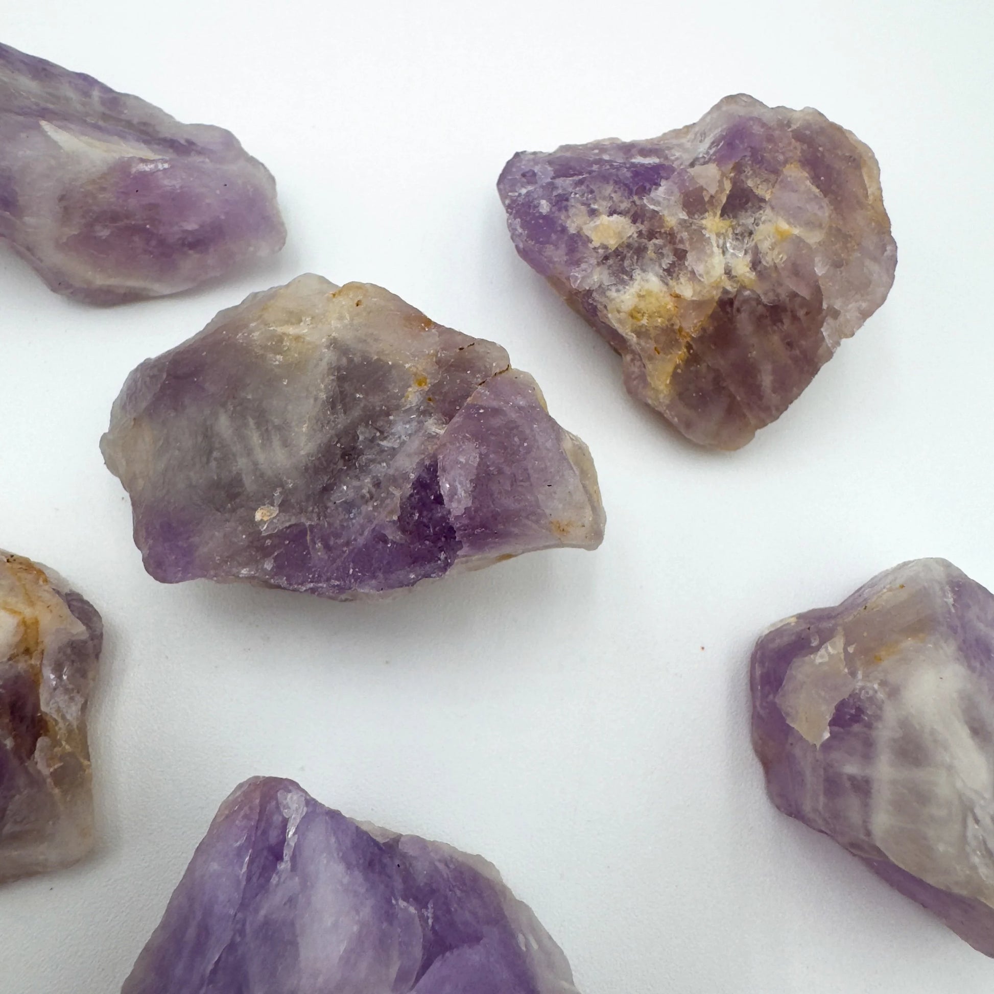 In-hand view of a Amethyst raw stone held against natural backdrop.