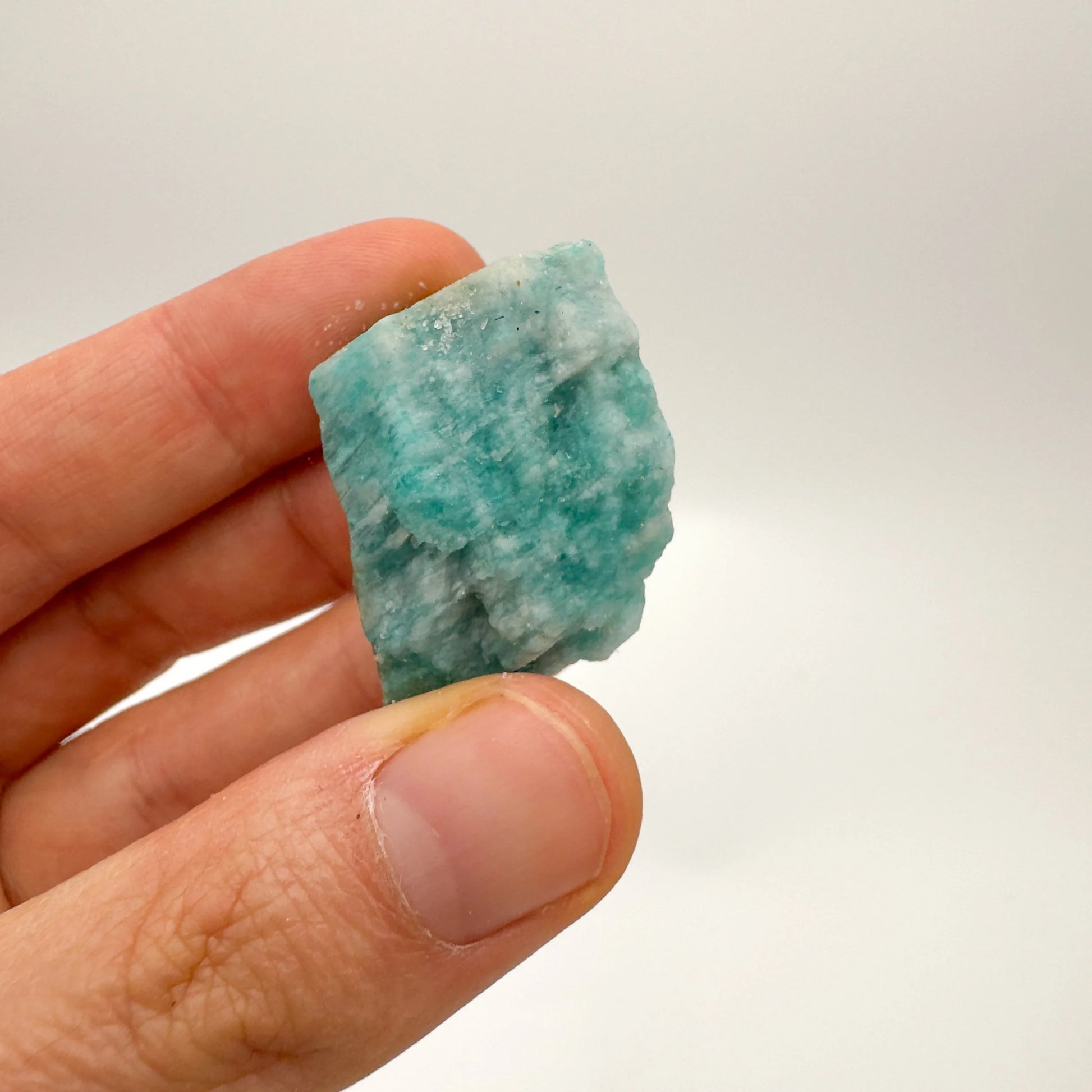 Grade a amazonite raw held in hand for size reference