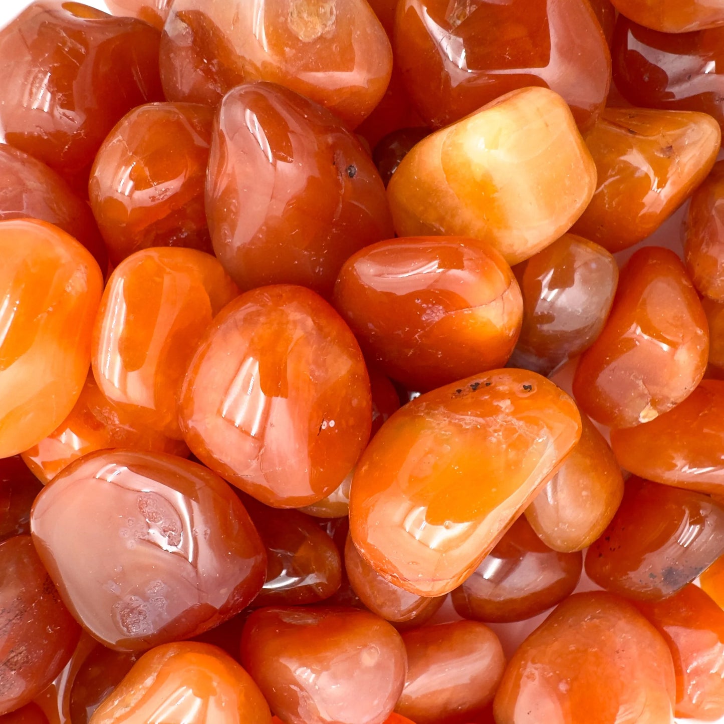 Close-up detail of Grade AA Carnelian tumbled stone showing natural orange, red tones and texture