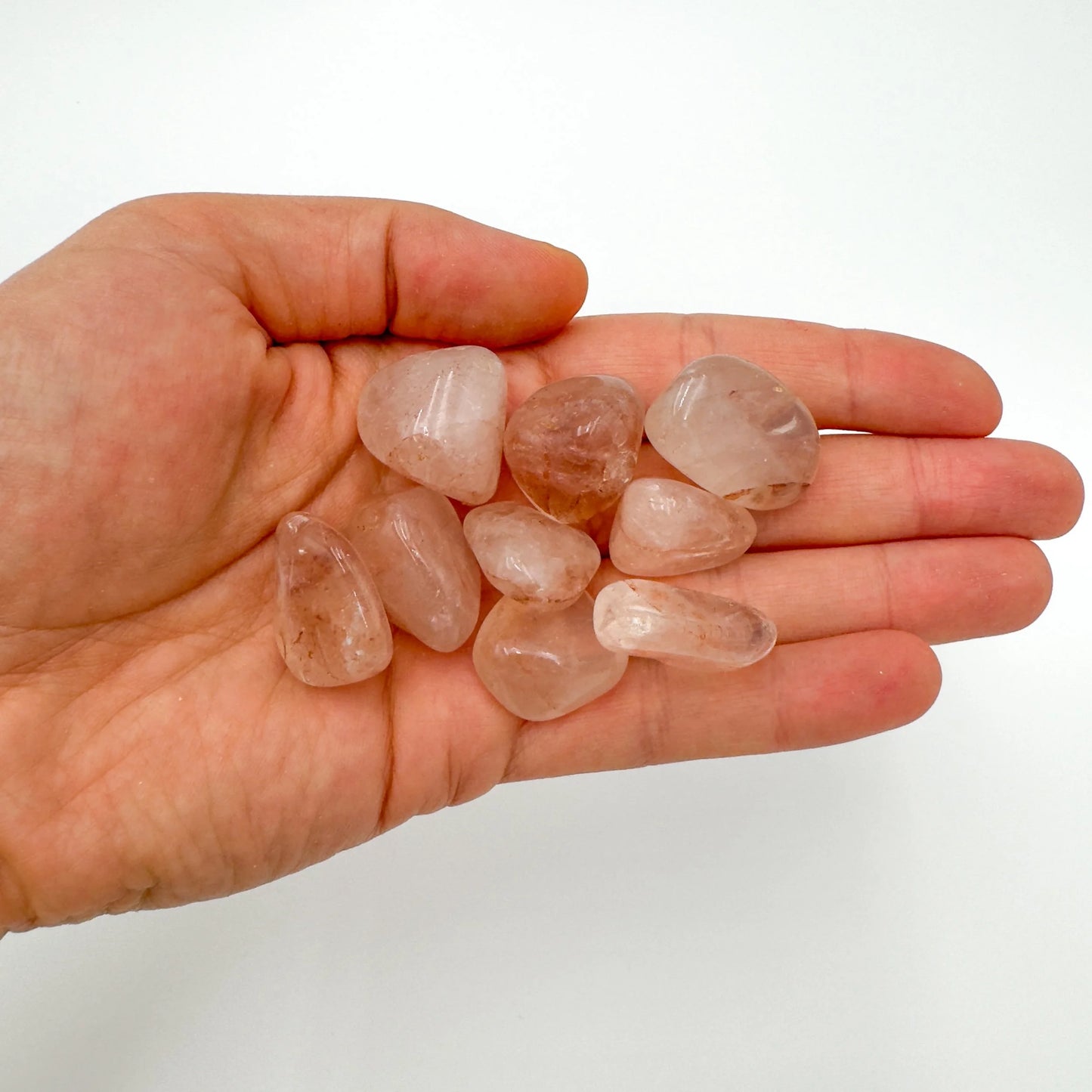 Palm-scale view of a single Fire Quartz tumbled stone hand-selected from Alaotra-Mangoro, Madagascar.