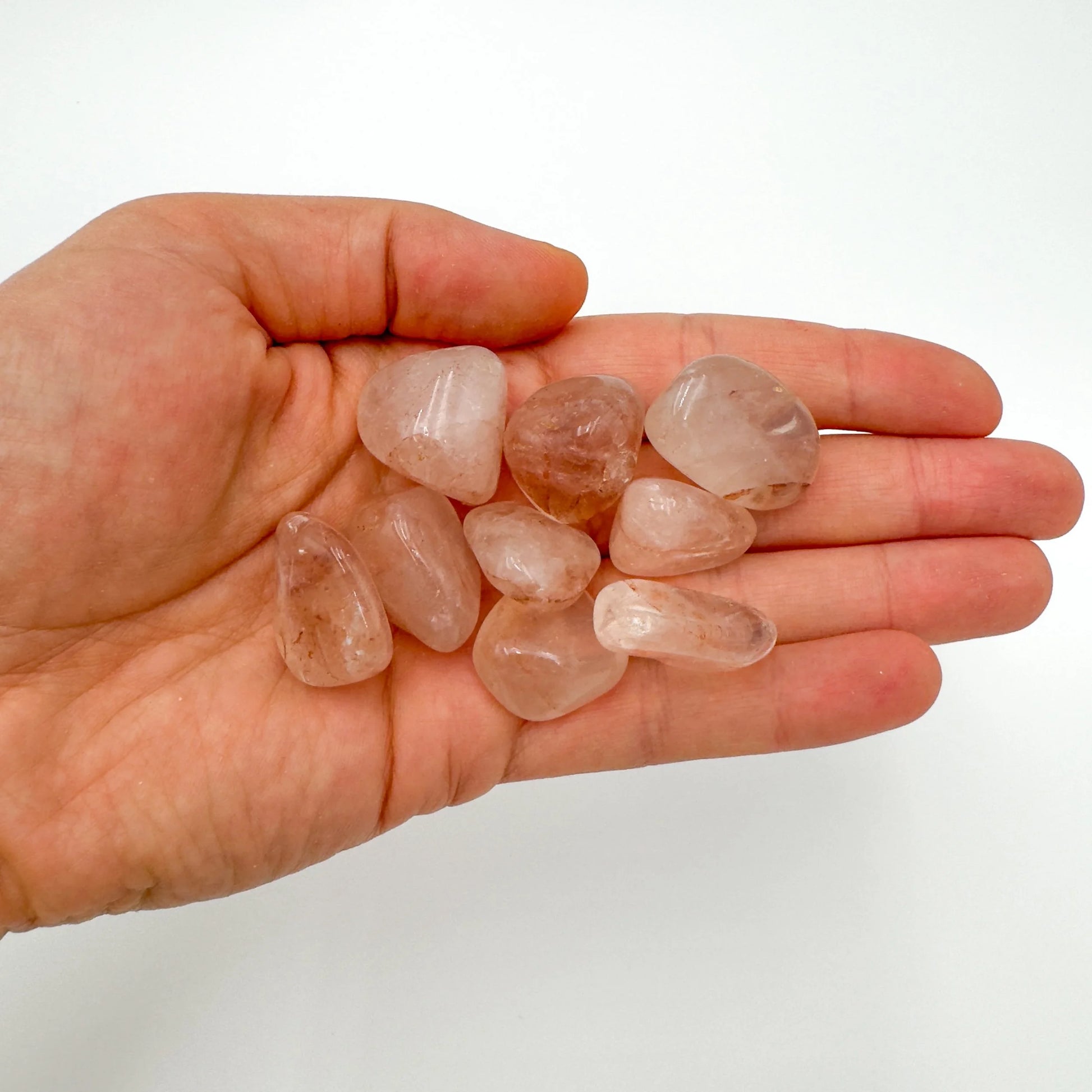 Palm-scale view of a single Fire Quartz tumbled stone hand-selected from Alaotra-Mangoro, Madagascar.