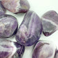 Hand-scale view of Chevron Amethyst tumbled stone, from Copperbelt Province, Zambia, associated with Meditation, shown for proportion against the hand.