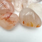 Side angle of Grade AA Fire Quartz tumbled stone, showing earthy tone, often kept for Grounding and Confidence.