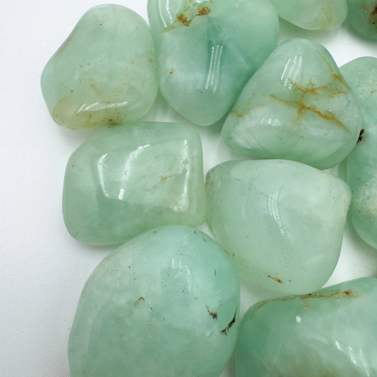 Underside view of Grade AA green Prehnite tumbled stone, showing color depth.