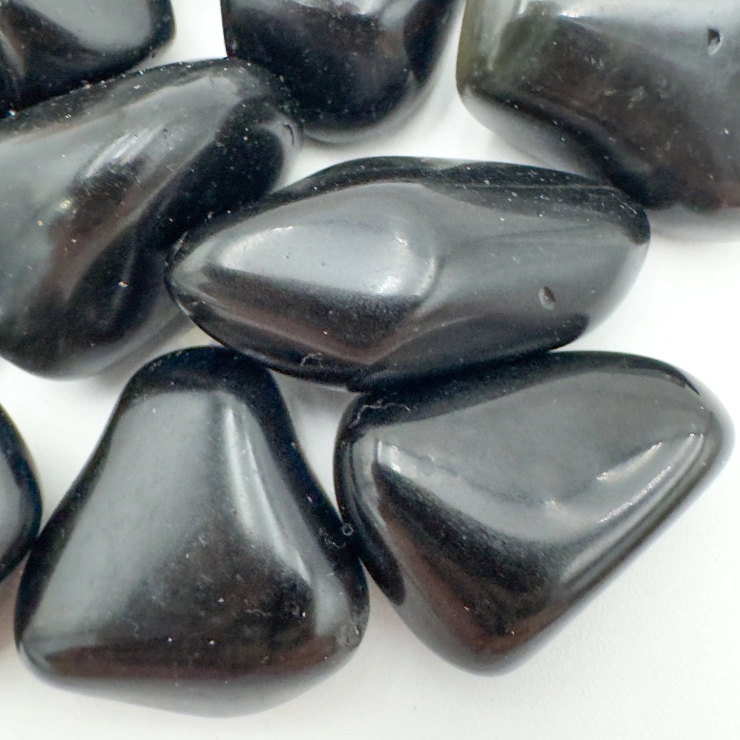 Palm-scale view of a Rainbow Obsidian tumbled stone held against natural backdrop, sourced from Mexico.