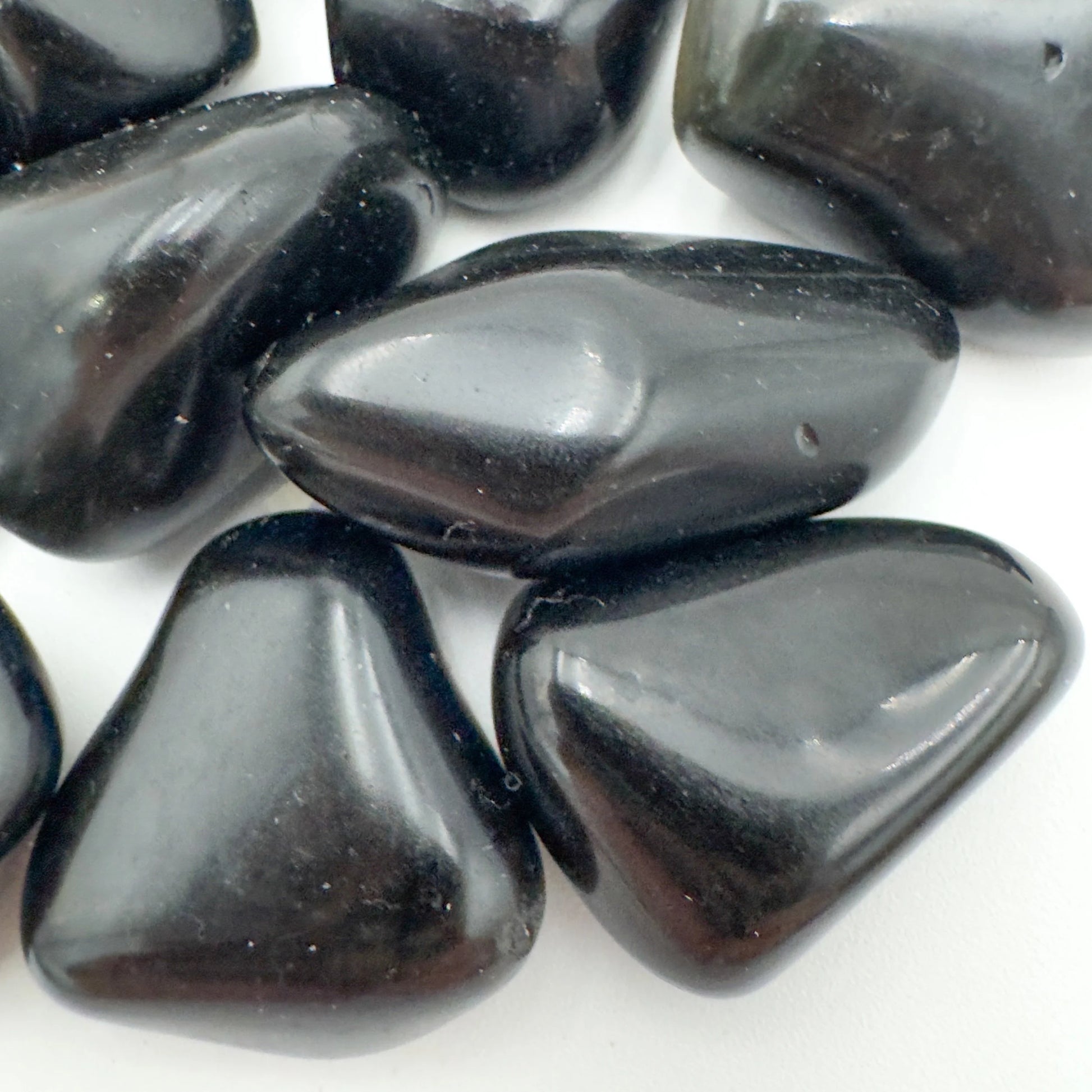 Palm-scale view of a Rainbow Obsidian tumbled stone held against natural backdrop, sourced from Mexico.