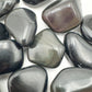 Edge view of Rainbow Obsidian tumbled stone, showing color depth.