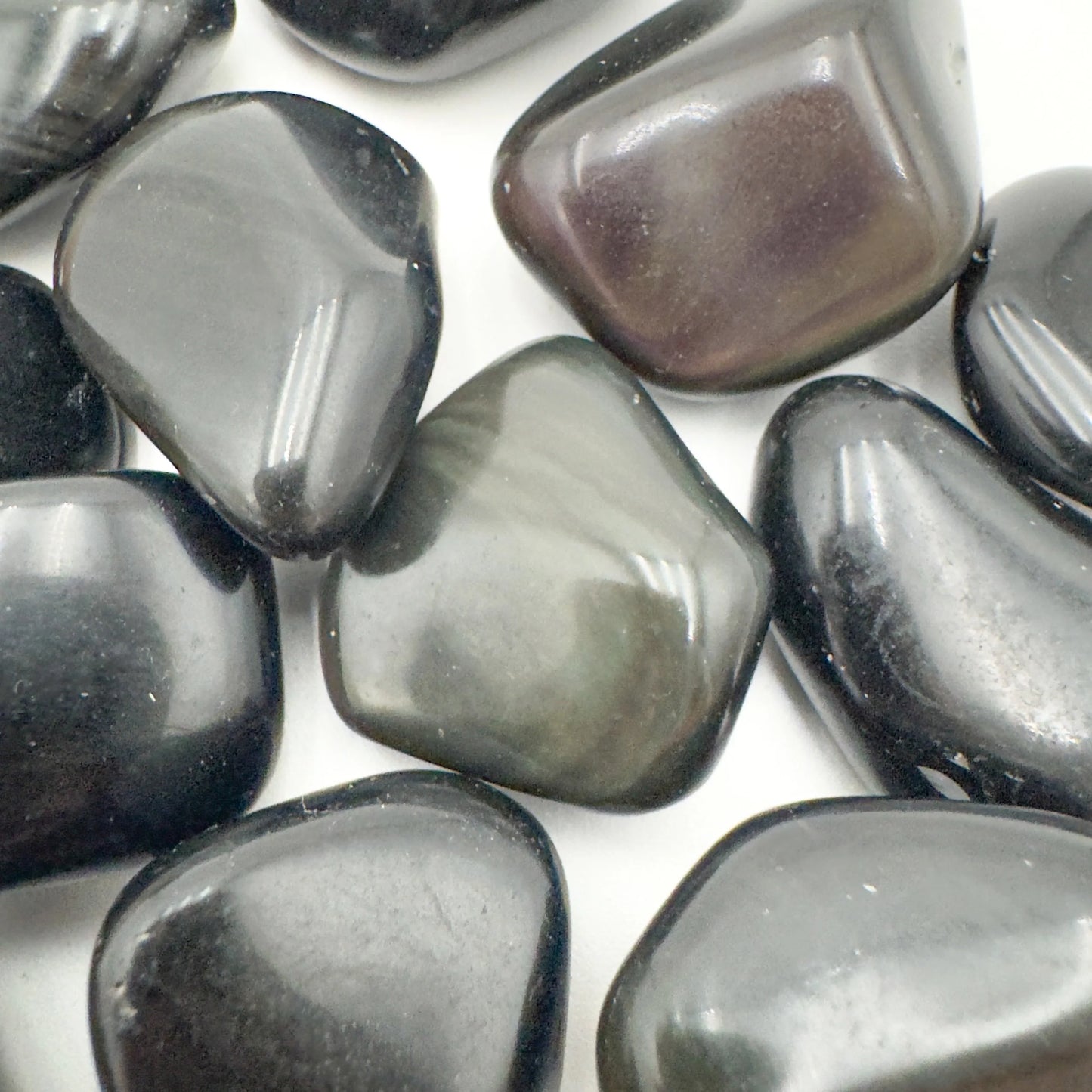 Edge view of Rainbow Obsidian tumbled stone, showing color depth.