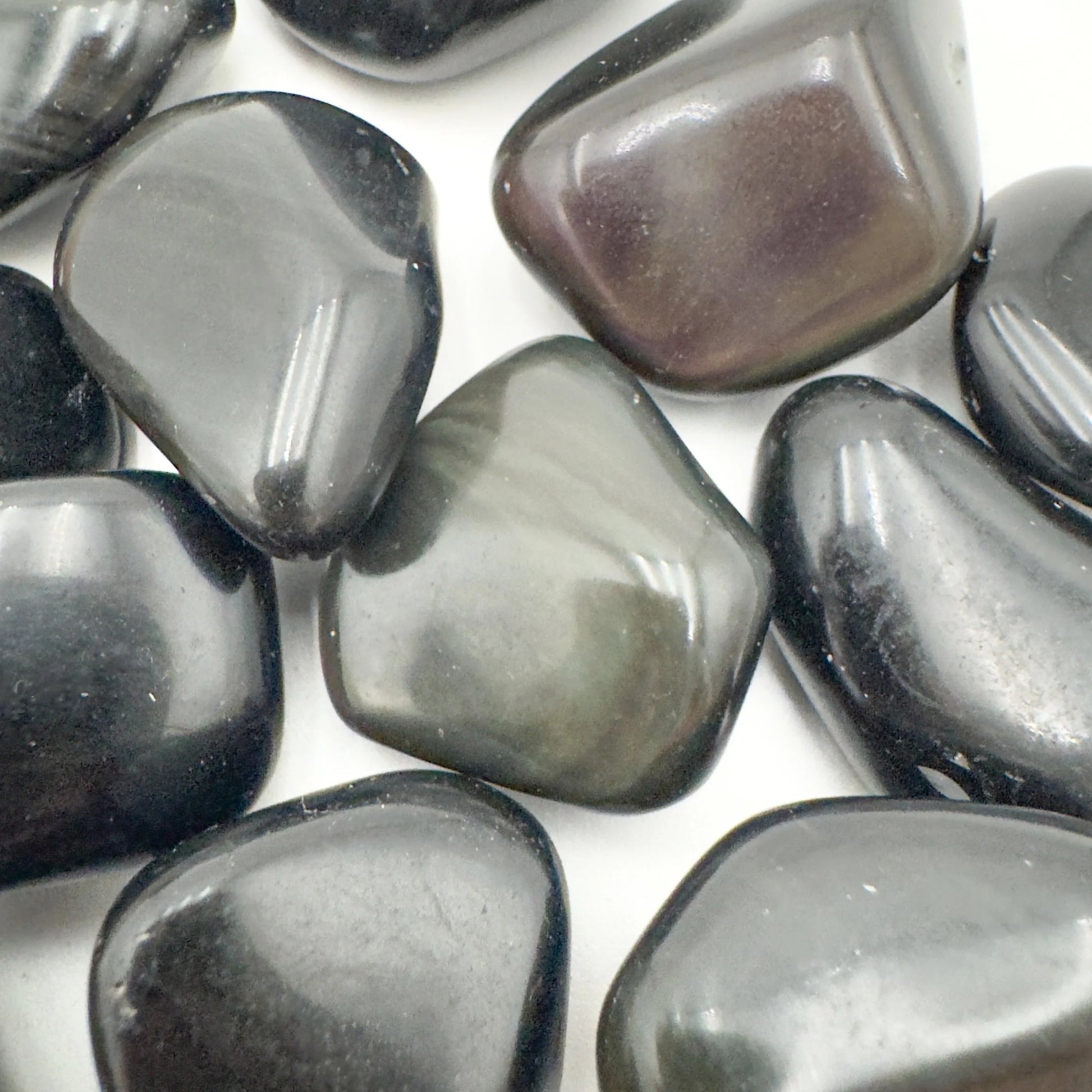 Edge view of Rainbow Obsidian tumbled stone, showing color depth.