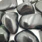 Overhead angle of black Rainbow Obsidian tumbled stone, showing subtle veining.