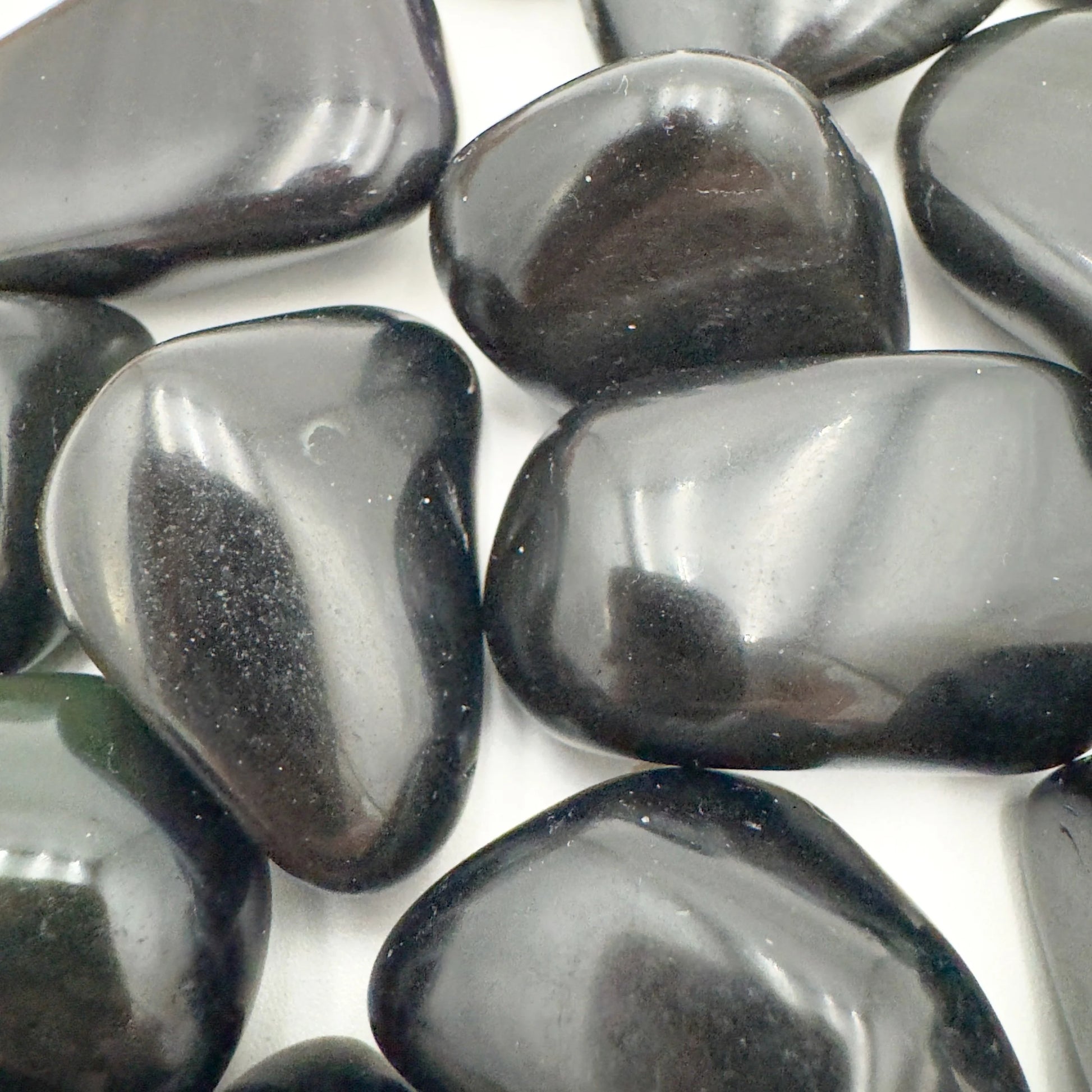Overhead angle of black Rainbow Obsidian tumbled stone, showing subtle veining.