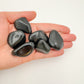 Lifestyle still of Rainbow Obsidian tumbled stone, showing the full body of the piece.