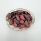 Tight crop of pink Rhodonite tumbled stone, Zimbabwe-sourced, showing characteristic patterning.