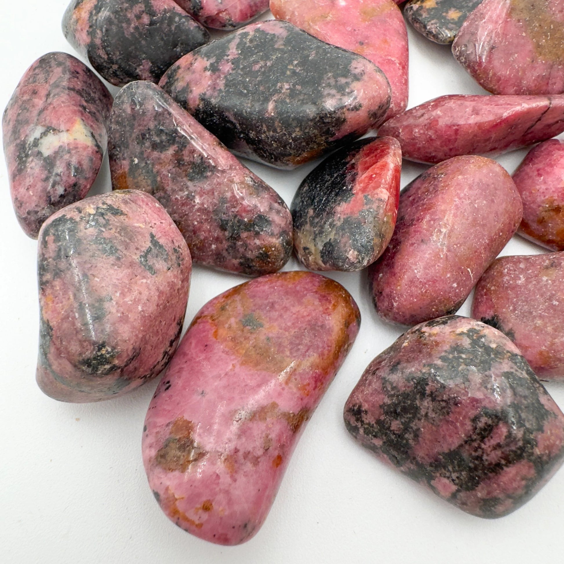 Lateral view of Grade AA Rhodonite tumbled stone, showing natural inclusions, hand-selected from Masvingo, Zimbabwe.