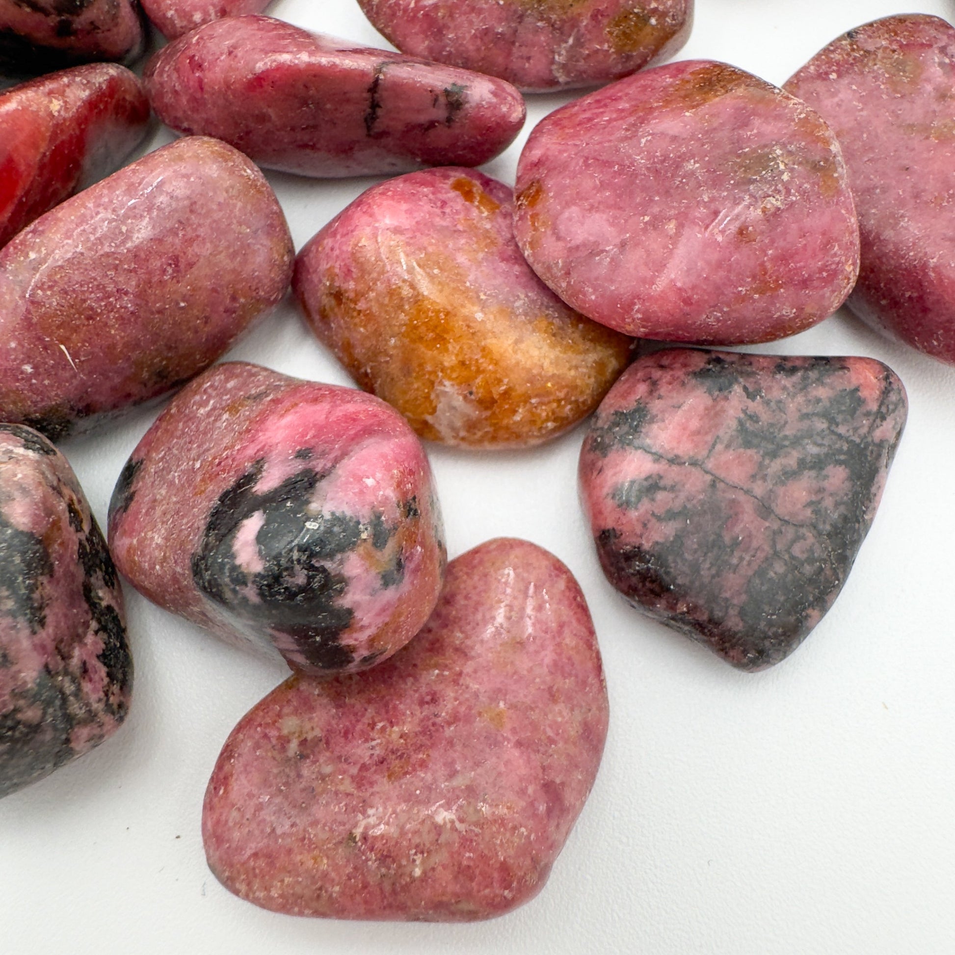 Bird's-eye view of Grade AA Rhodonite tumbled stone, showing natural texture.
