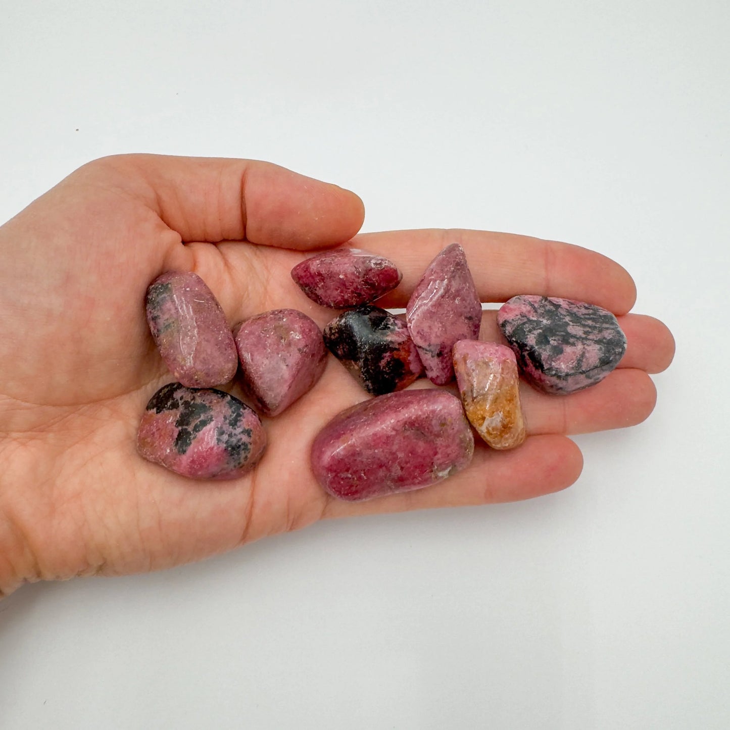 Natural light view of one Rhodonite tumbled stone for scale, from Masvingo, Zimbabwe.